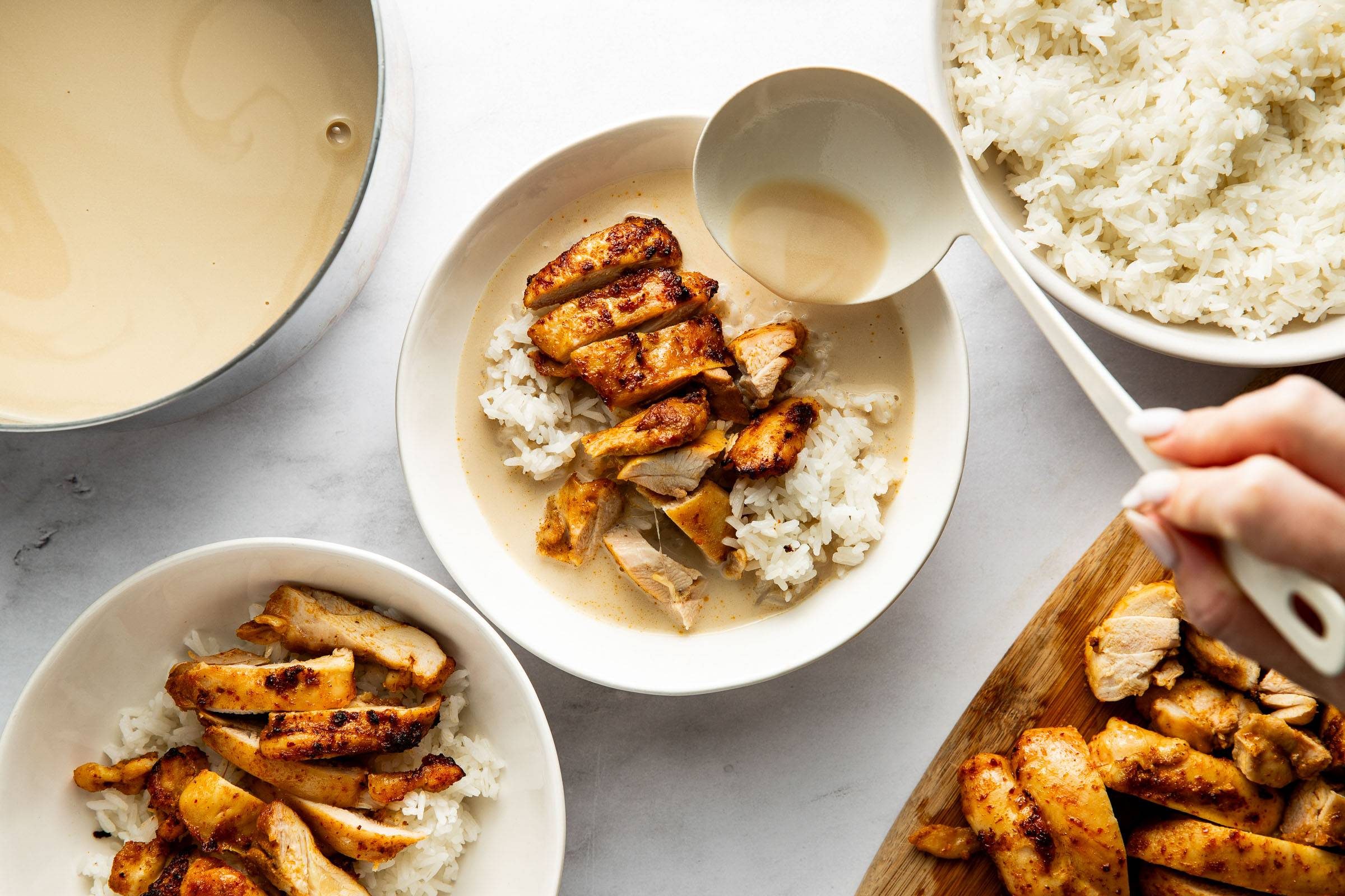 Ladling broth into bowls with chicken and rice.
