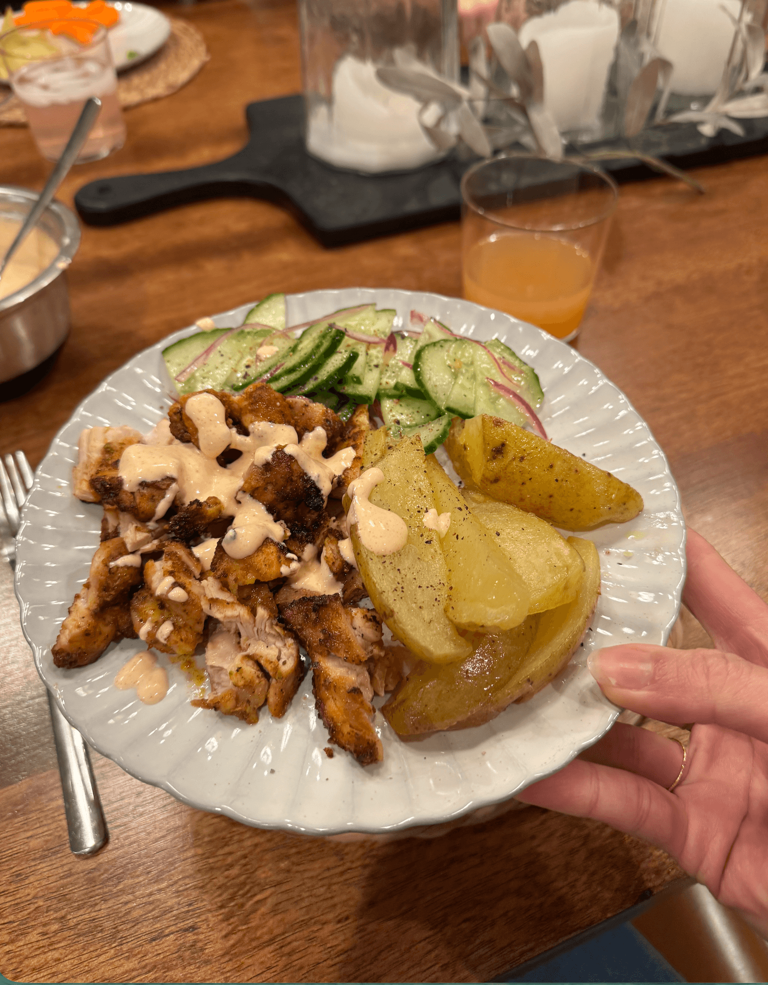 Chicken thighs, potatoes, and cucumber salad on a plate.