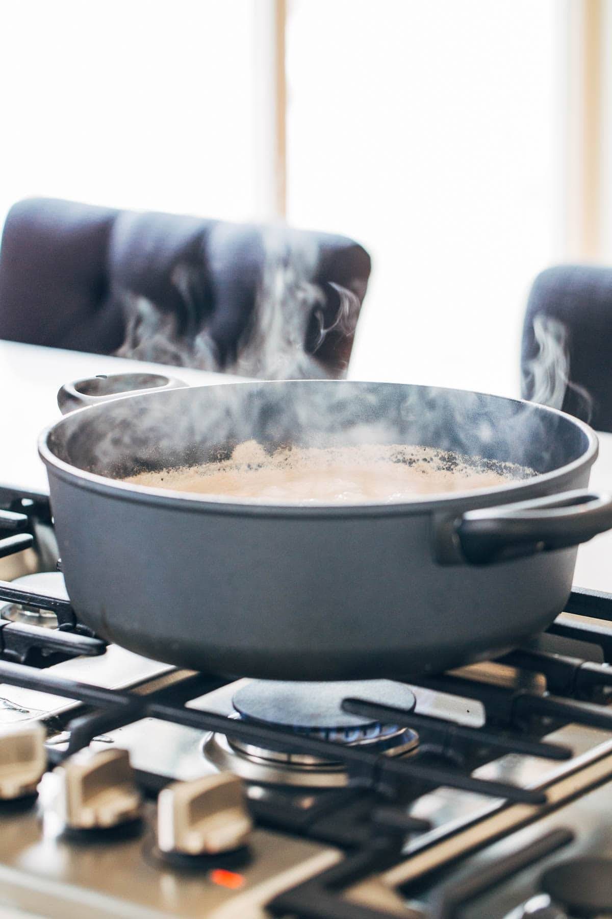 Pot of boiling sauce over a stove top.