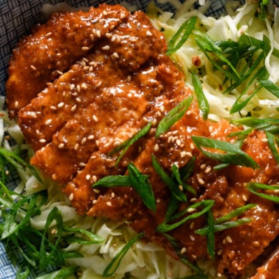 Gochujang chicken on a bowl of shredded cabbage.