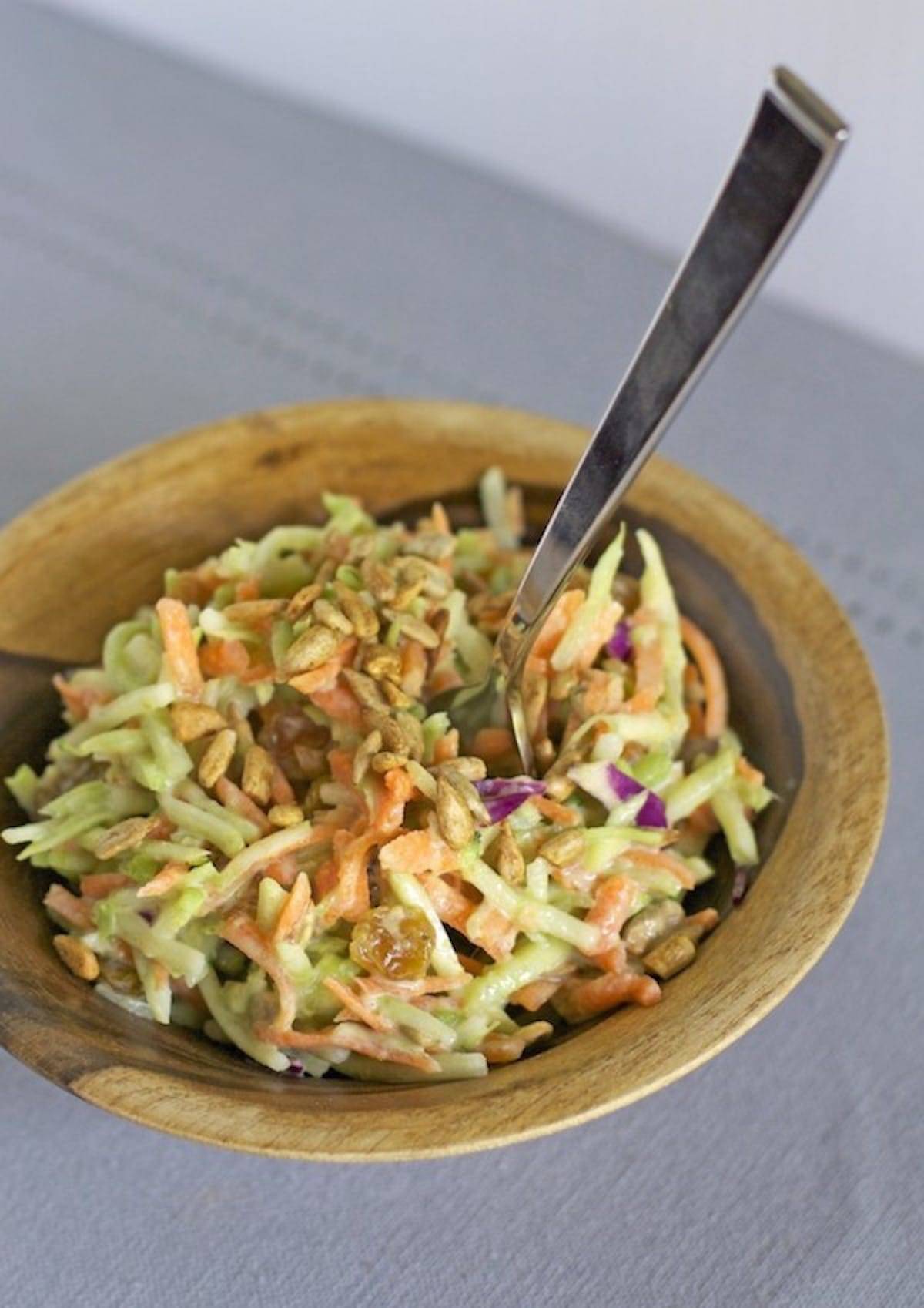 Green curry salad in a wooden bowl with a fork.
