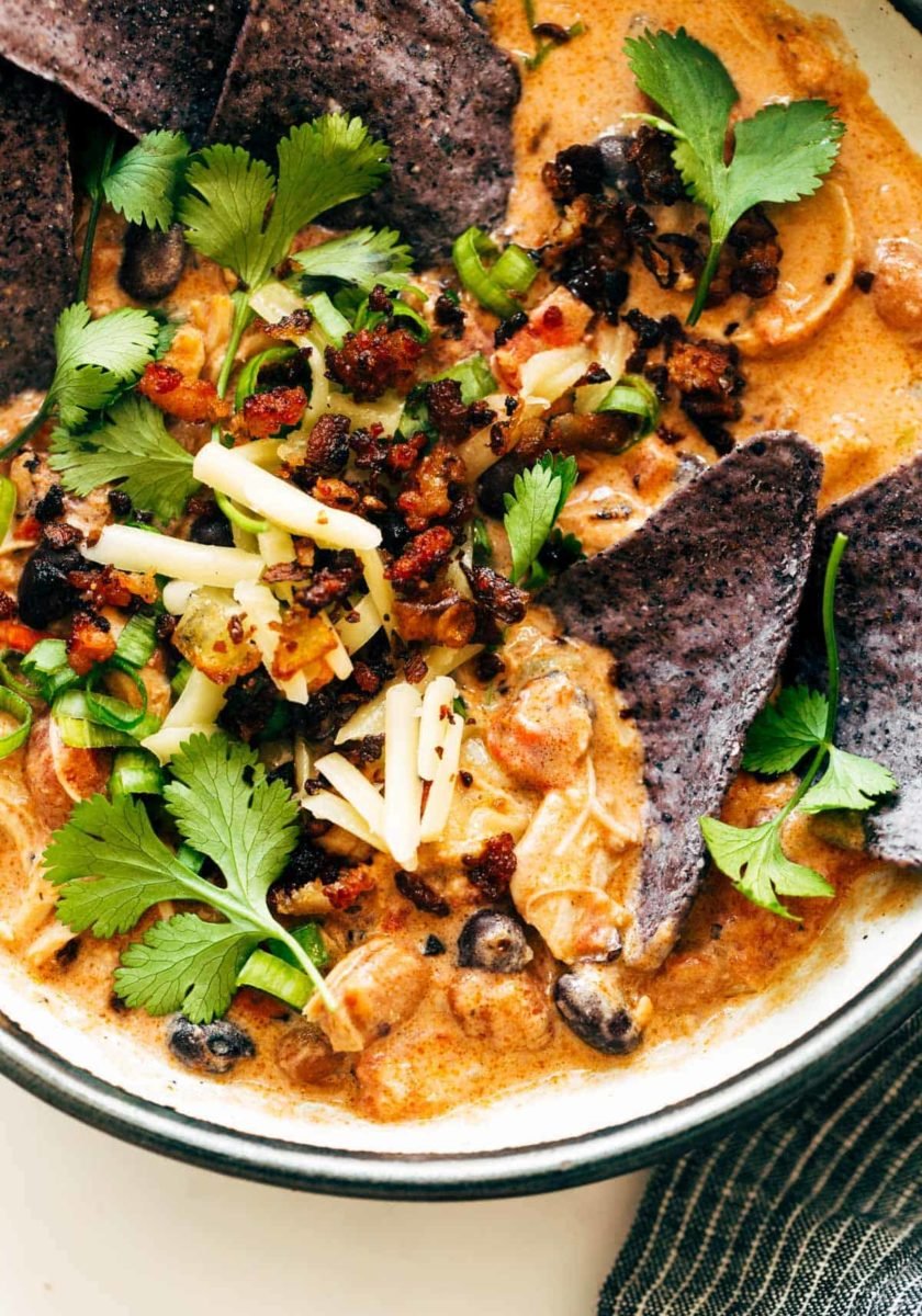 Chips in a bowls of chili and garnishments.