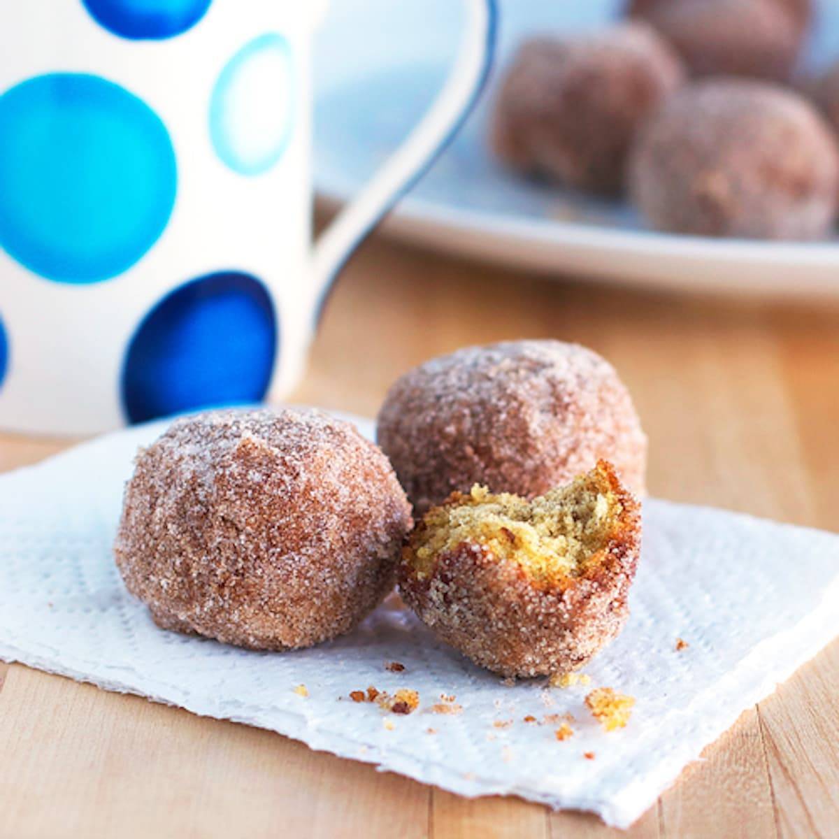Cinnamon sugar donut balls with crumbs on a napkin.